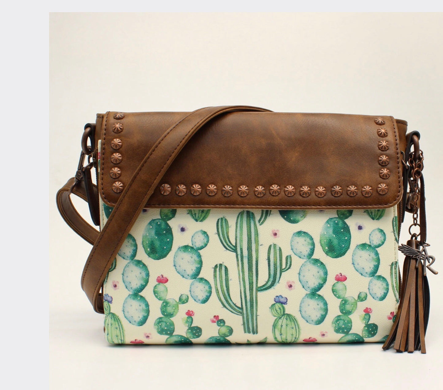 D330001302 Details Cactus Collection Angel Ranch Crossbody Brown Measures: 11 x 3 x 8-1/2 Green Cacti with Pink Flower Accents Ivory Background Adjustable Strap Zippered Front with Cell Pouch and Credit Card Slots Conceal Carry Pocket on Back